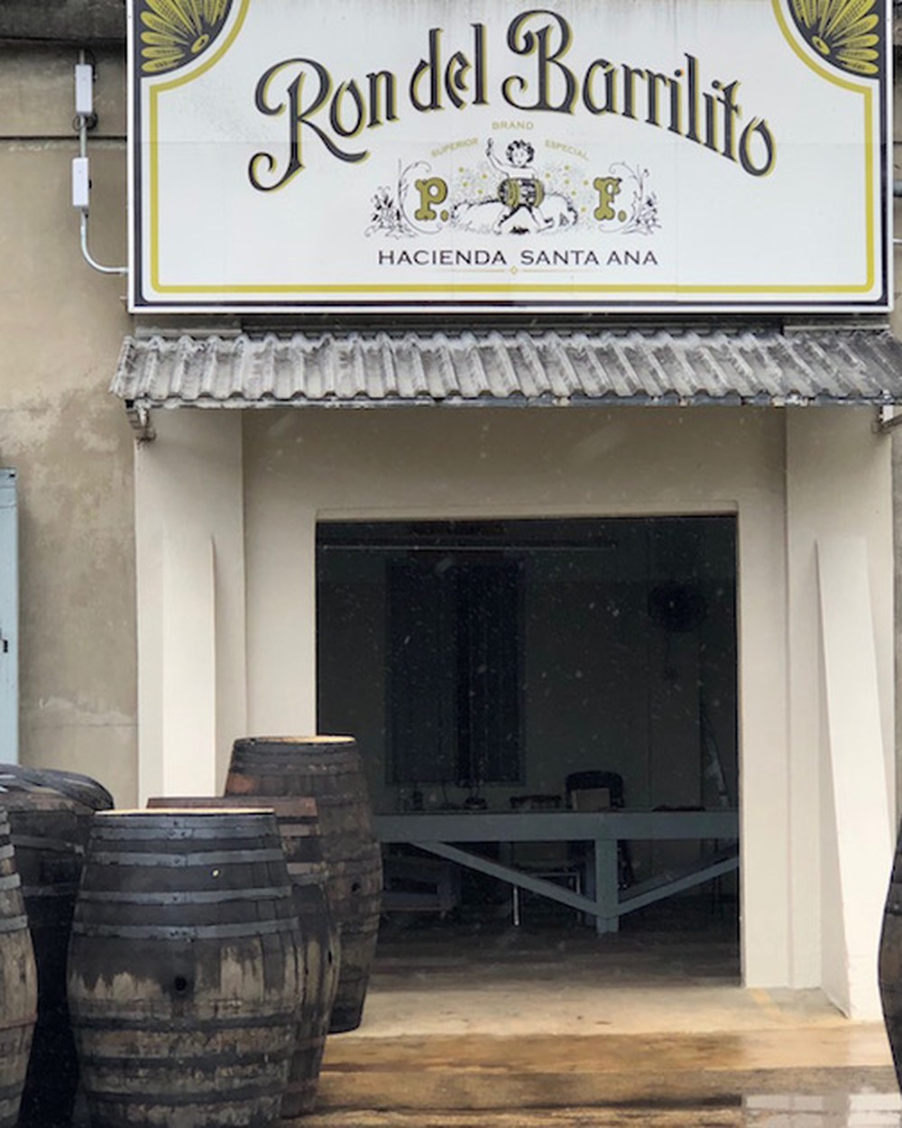 The Ron del Barrilito distillery at Hacienda Santa Ana, with aging barrels beneath the sign